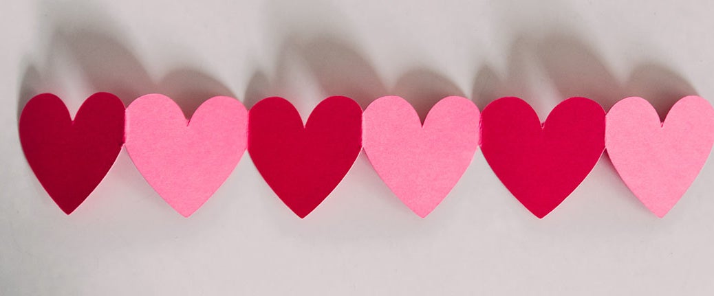 Red and pink paper hearts in line on a white background.
