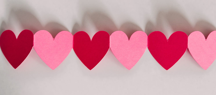 Red and pink paper hearts in line on a white background.