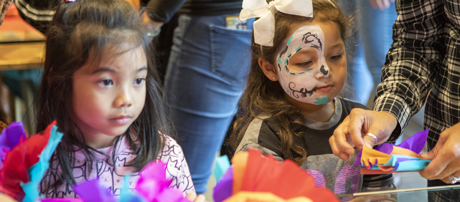 Two children assemble paper flowers during the Dia de los Muertos community festival.