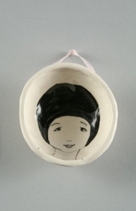 Single vessel from the Waiting Lady series. Shallow, small white porcelain bowl with the face of a female figure in black line on the interior.