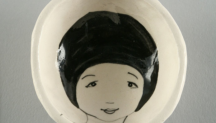 Single vessel from the Waiting Lady series. Shallow, small white porcelain bowl with the face of a female figure in black line on the interior.