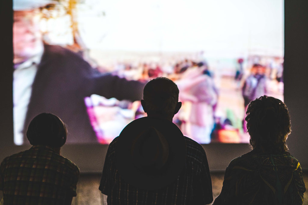 Three people sit in front of a blurry screen. Photo by Aneta Pawlik on Unsplash.