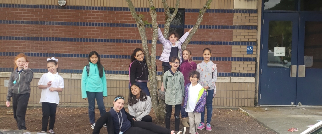 Eleven elementary school children pose outside of their school after a Sketch Club session.