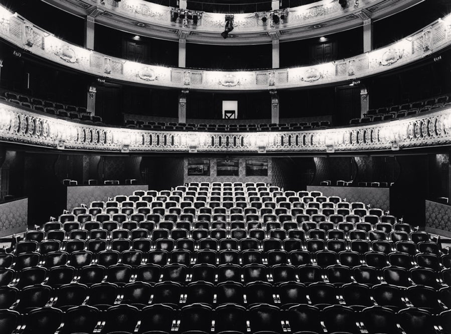 Image of the interior of the seats and boxes in an empty theater as seen from the stage.