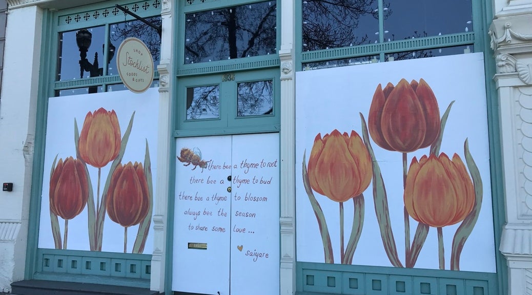 White painted panels decorated with orange and red tulips cover storefront windows