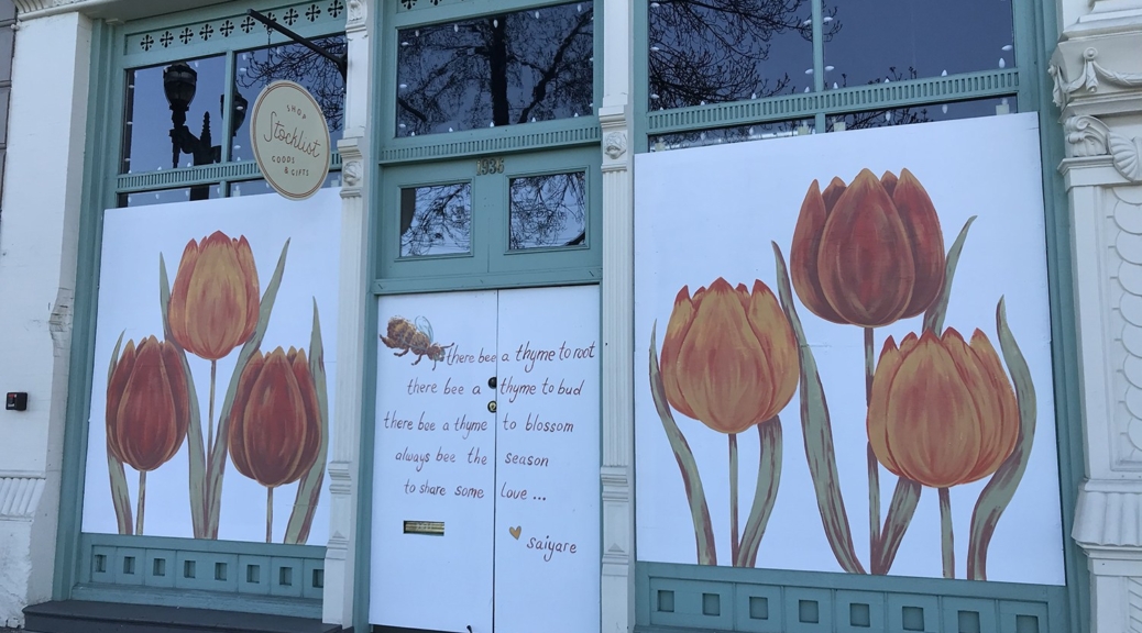 White painted panels decorated with orange and red tulips cover storefront windows