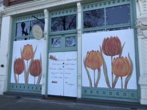 White painted panels decorated with orange and red tulips cover storefront windows