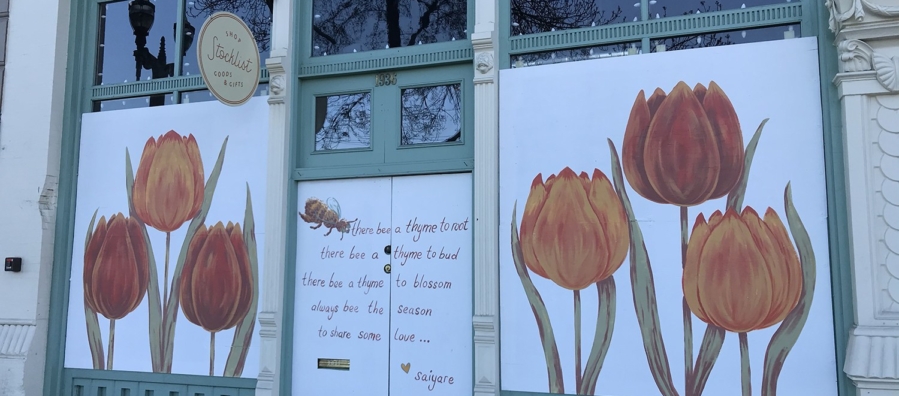 White painted panels decorated with orange and red tulips cover storefront windows