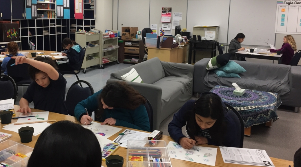 Students sit at tables working on art projects during Sketch Club