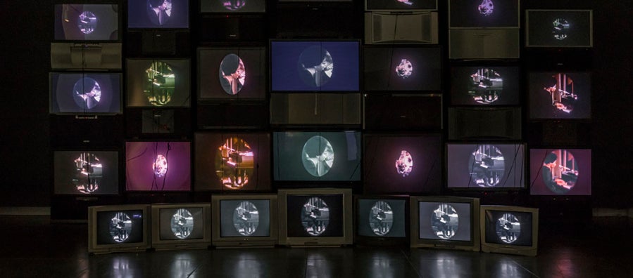 Photograph of video installation exhibition, "Black is the Color," made up of 28 salvaged televisions.