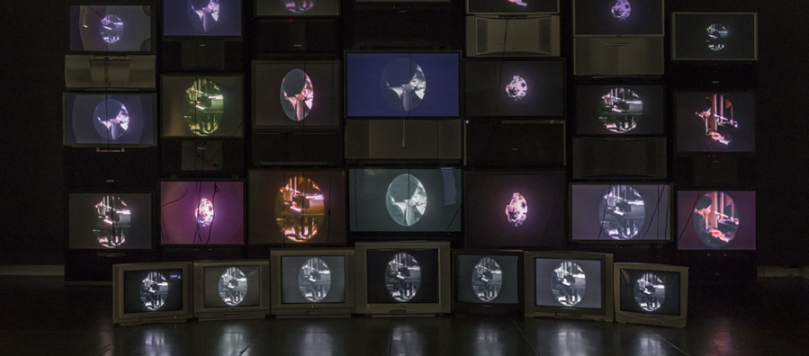 Photograph of video installation exhibition, "Black is the Color," made up of 28 salvaged televisions.