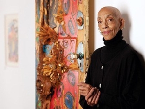 Artist Aminah Robison pictured in a gallery with one of her artworks