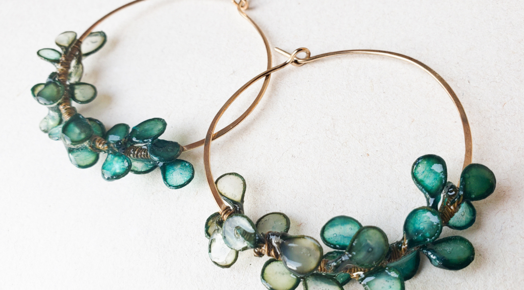 Photograph of large hoop earrings decorated with blue-green leaf-like shapes