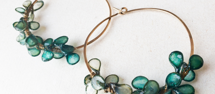 Photograph of large hoop earrings decorated with blue-green leaf-like shapes