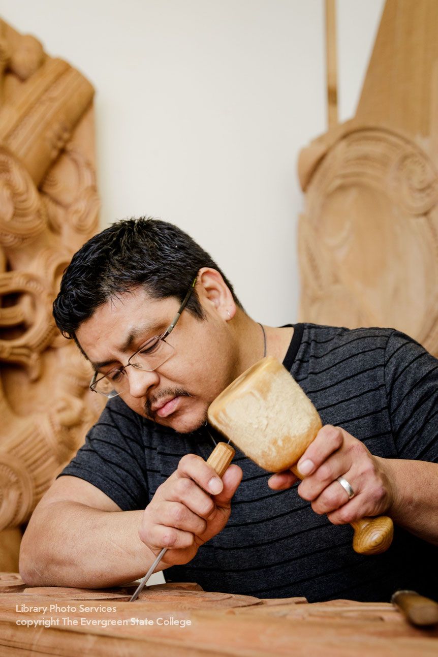 Photo of artist Alexander McCarty in the process of carving a sculptural piece.
