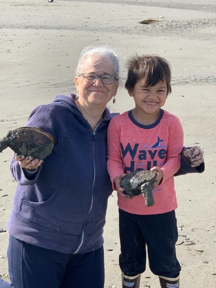 Photo of artist Melissa Peterson posing with a young child on the beach.