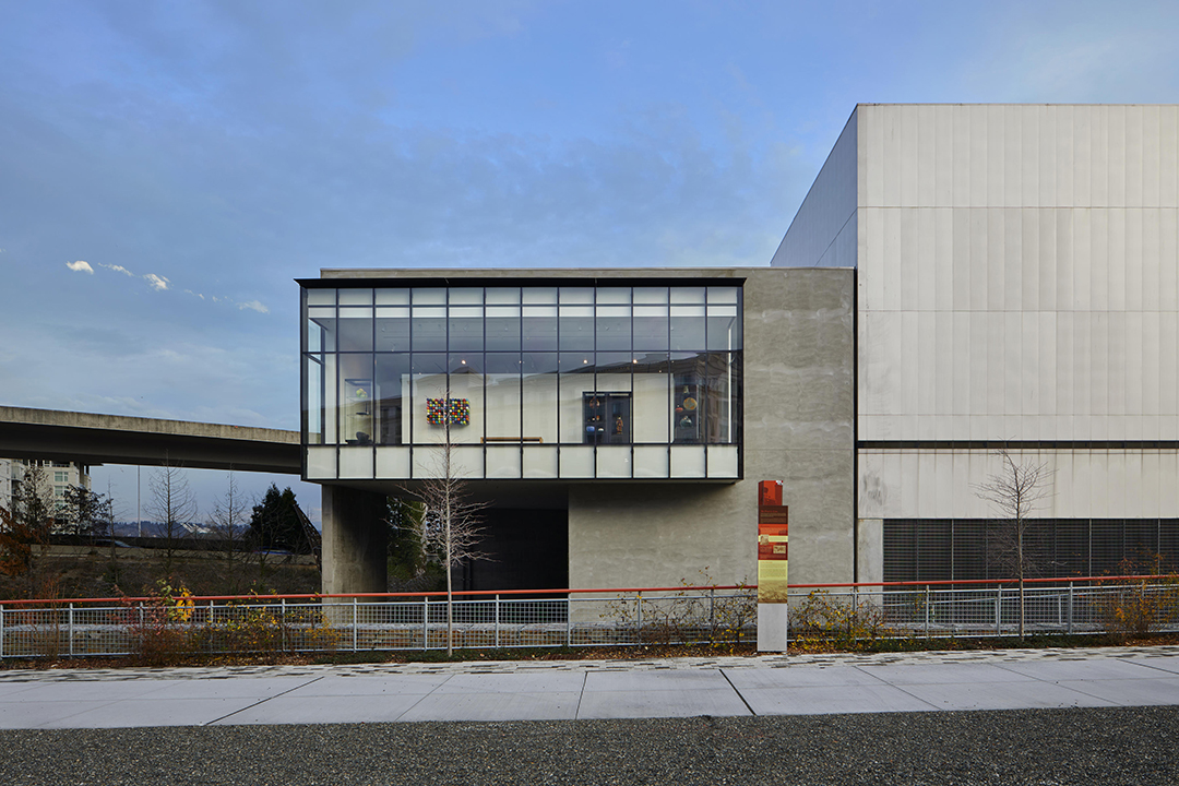 Exterior shot of the Rebecca and Jack Benaroya Wing. Glass works of art are visible through the floor to ceiling windows.