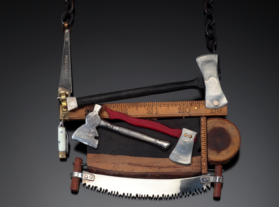 Color photo of necklace featuring miniature axes, rulers, saws, wood, and other tools