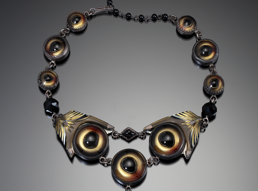 Color photo of a black and gold necklace stylized to look like glass eyeballs by artist Nancy Worden