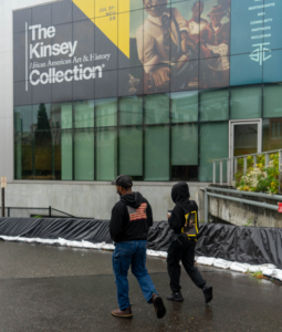 Image of two people wearing black hooded sweatshirts with screen printed designs