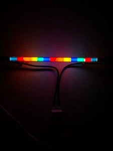 Color photo of a multicolor neon tube hung up against a dark background.