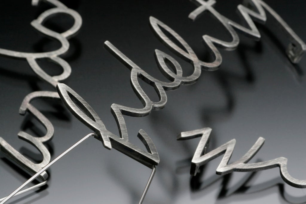 Sterling silver and stainless steel brooches spelling out "fidelity," "ardor," and "wit."