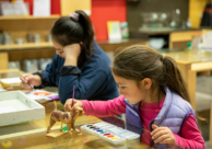 Color photo of two children engaged in artmaking activities in the TAM Studio