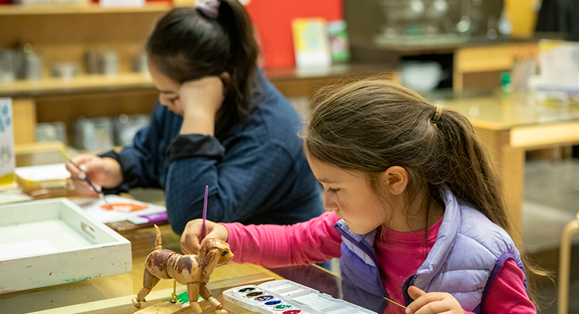 Color photo of two children engaged in artmaking activities in the TAM Studio